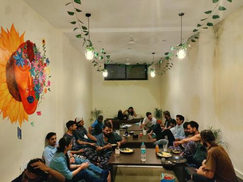 eine Gruppe von Menschen, die in einem Raum an einem Tisch sitzen in der Unterkunft Tatsat Hostel in Rishikesh