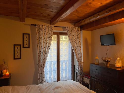 塞薩納托里內塞的住宿－Appartamento nel centro storico - Cesana Torinese，一间卧室设有一张床和一个带电视的窗户。