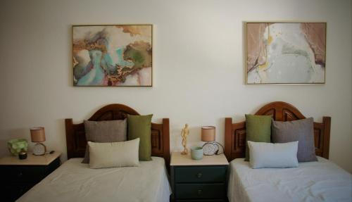 two beds in a room with two lamps on the wall at Casa das Laranjeiras in Mértola