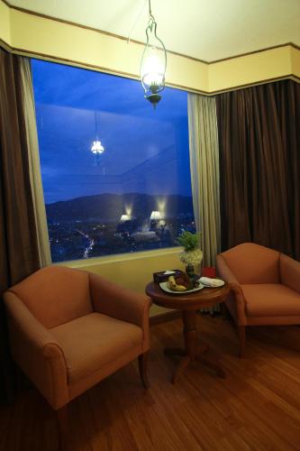 a living room with a large window with a table and chairs at Duangtawan Hotel Chiang Mai in Chiang Mai