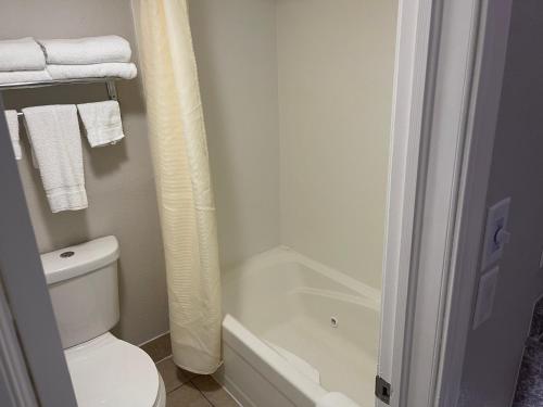 a bathroom with a white toilet and a bath tub at Stratford House Inn in Branson