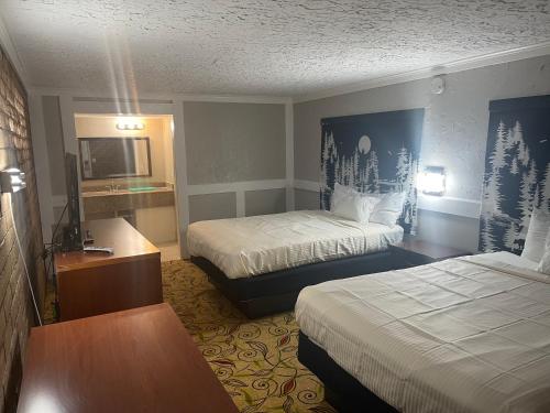 a hotel room with two beds and a television at Stratford House Inn in Branson