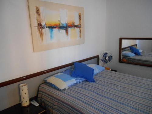 a bedroom with a bed with blue and white pillows at Apart-Hotel para 3 pessoas in Fortaleza