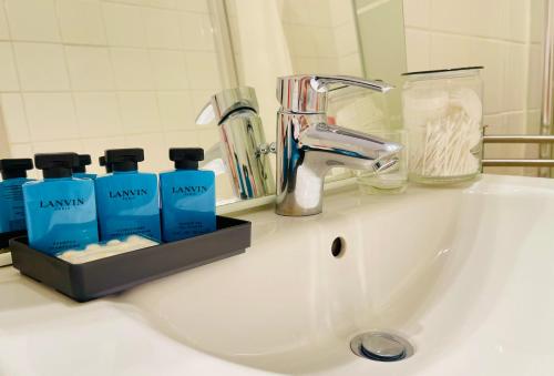 - un lavabo avec des bouteilles de savon bleues et un miroir dans l'établissement Le Croix Rousse Jacquard, à Lyon