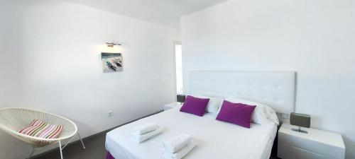 a white bedroom with a white bed with purple pillows at Sand Volcano Villa 2 in La Oliva