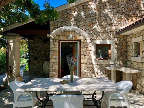 a table and chairs in front of a stone building at STONE HOUSE reTREAT in Mali Lošinj