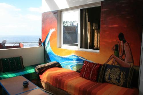 a room with a couch and a window and the ocean at Surf & Travel Camp in Taghazout