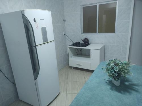 a white refrigerator in a kitchen with a table at Apartamento amplo pé na areia - Itapema 180m da Praia in Itapema