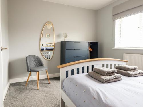1 dormitorio con cama, espejo y silla en 4 Plas Newydd, en Llandudno