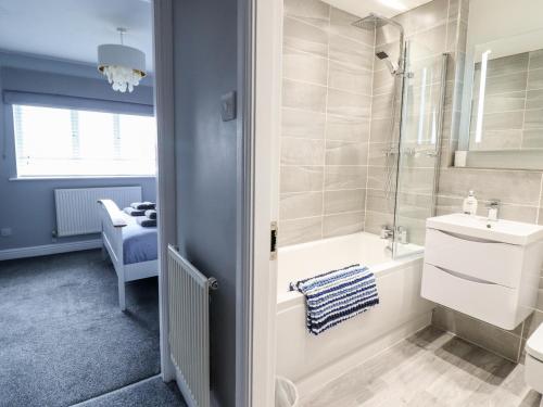 een badkamer met een bad, een wastafel en een douche bij 4 Plas Newydd in Llandudno