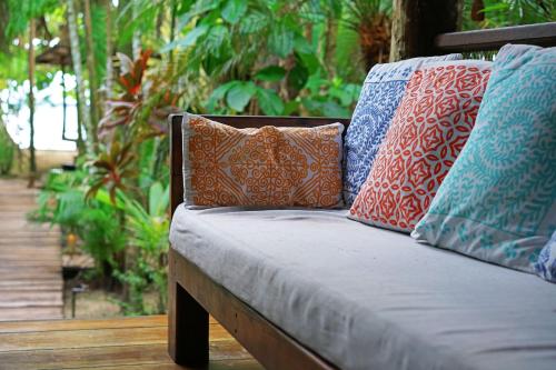 a bench with colorful pillows on it with a garden at Casa Cayuco Eco-Adventure Lodge in Bocas del Toro