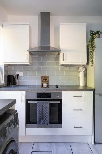 a kitchen with white cabinets and a stove at Fully Refurbished North Belfast Home in Belfast