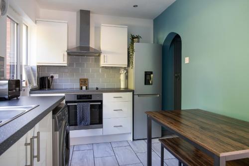 a kitchen with white cabinets and a wooden table at Fully Refurbished North Belfast Home in Belfast