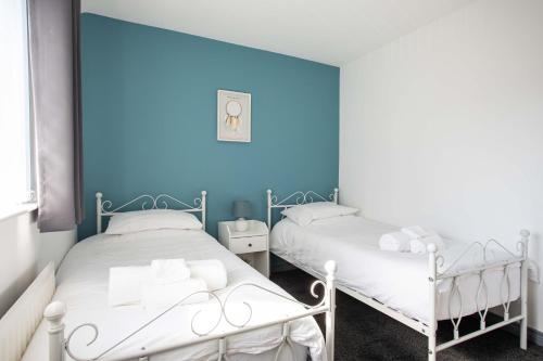 2 łóżka w pokoju z niebieską ścianą w obiekcie Fully Refurbished North Belfast Home w mieście Belfast
