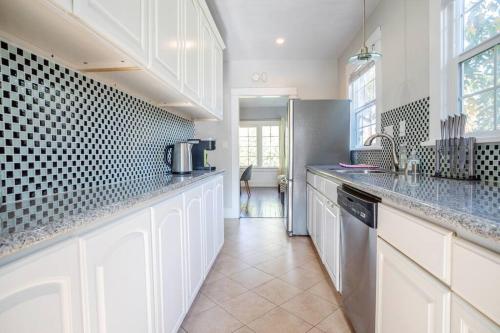 a kitchen with white cabinets and a refrigerator at Hollywood house with parking - walk to attractions in Los Angeles