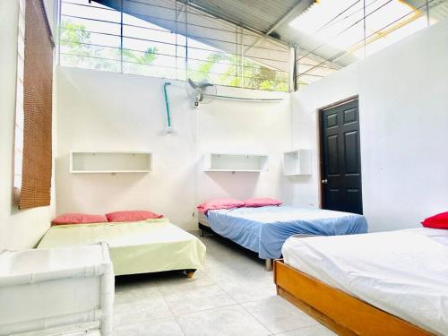 トカイマにあるFinca La Felicidadのベッド3台と窓が備わる客室です。
