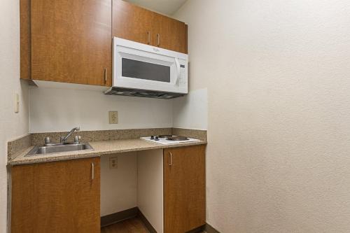 a small kitchen with a sink and a microwave at HomeTowne Studios by Red Roof Dallas - Irving in Irving