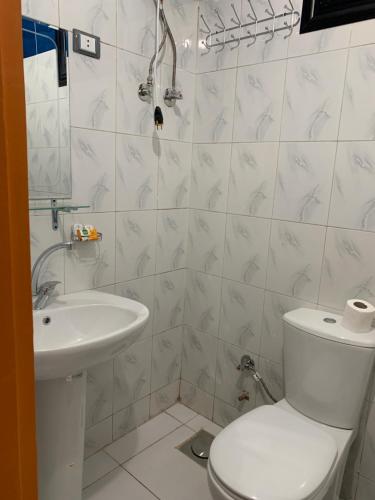 a white bathroom with a toilet and a sink at Royal Hotel in Qena