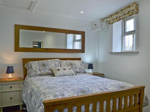 Schlafzimmer mit einem Bett und einem Wandspiegel in der Unterkunft The Dairy - Uk30867 in St Bees
