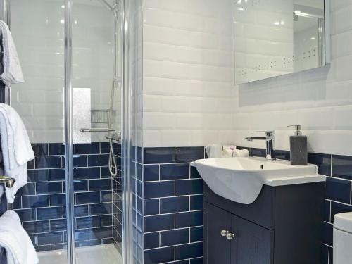 ein blau gefliestes Bad mit einem Waschbecken und einer Dusche in der Unterkunft The Dairy - Uk30867 in St Bees