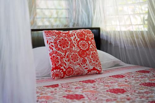 a red and white pillow sitting on top of a bed at Casa Cayuco Eco-Adventure Lodge in Bocas del Toro