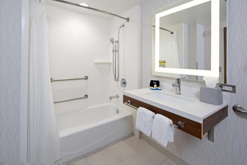 a white bathroom with a tub and a sink and a mirror at Holiday Inn Express Hotel & Suites Atascadero by IHG in Atascadero