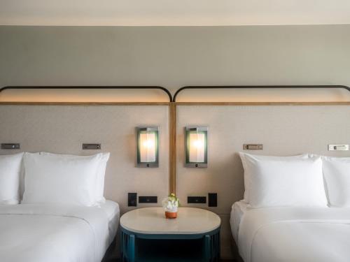 two beds in a room with a table between them at Crowne Plaza Resort Guam in Tumon