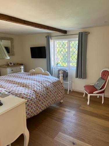 a bedroom with a bed and a chair and a window at Cosy Flint Cottage in Eastbourne