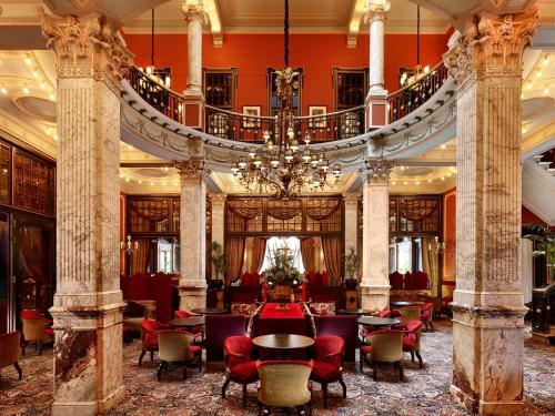 a lobby with a chandelier and tables and chairs at Hotel Des Indes The Hague in The Hague