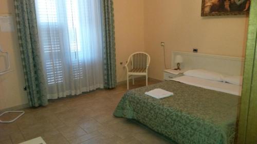 een slaapkamer met een bed, een stoel en een raam bij B&B Manzoni Resort in Brindisi