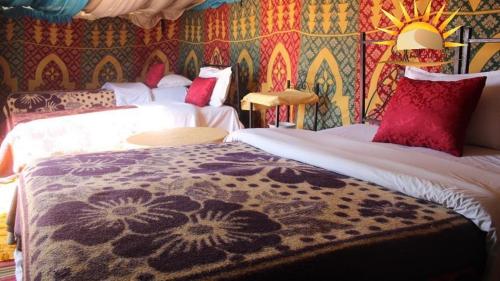 a bedroom with two beds and a patterned wall at Bivouac Karim Sahara in Zagora