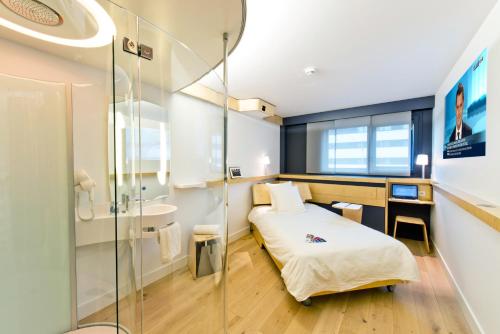 a small room with a bed and a shower at Nomad Paris Roissy CDG in Le Mesnil-Amelot