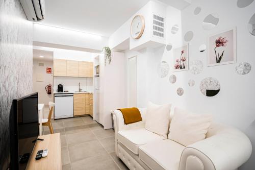 a living room with a white couch and a kitchen at dobohomes - Horcajuelo in Madrid