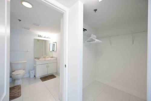 La salle de bains blanche est pourvue de toilettes et d'un lavabo. dans l'établissement Luxurious 1 Bed Apartment in Brickell • Ocean View, à Miami