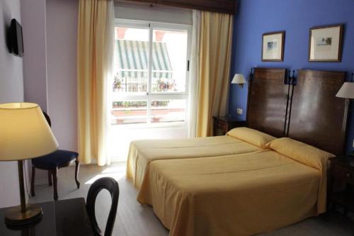a hotel room with a bed and a window at Hotel Iberia Plaza América in Cáceres