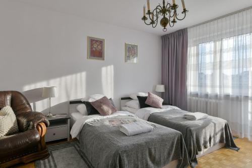 ワルシャワにあるP&O Apartments Marconich 1 Wilanowのベッドルーム1室(ベッド2台、椅子、シャンデリア付)