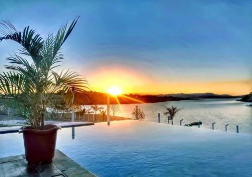 a swimming pool with a sunset in the background at RANCHO PARAISO Do ZIRINHO in Guapé
