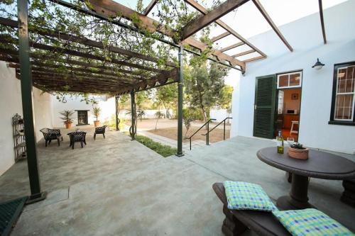 a patio with a wooden pergola and a table at CatsWhiskers in Graaff-Reinet