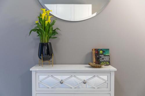 a vase with a plant on a dresser with a mirror at New & unique apartment - A 5 minutes ferry to capital city of Valletta in Senglea