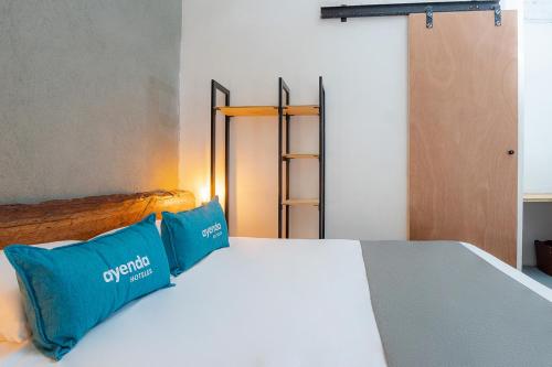 a bed with two blue pillows on top of it at Ayenda Flora Jaguar in Ibagué