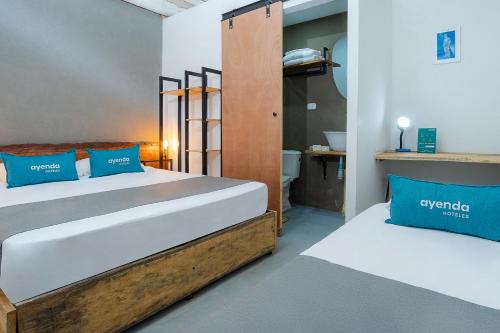 a bedroom with two beds with blue pillows at Ayenda Flora Jaguar in Ibagué