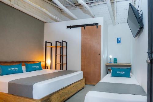 a bedroom with two beds and a tv on the wall at Ayenda Flora Jaguar in Ibagué