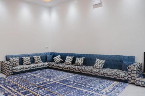 um sofá azul com almofadas num quarto em استراحة مارينا ضباب marinadababguest 