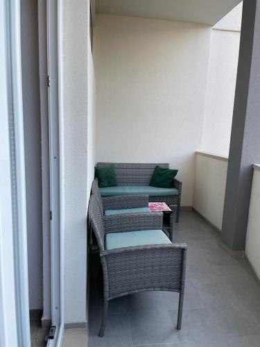 three wicker chairs with green pillows in a room at Apartman IVA in Tučepi