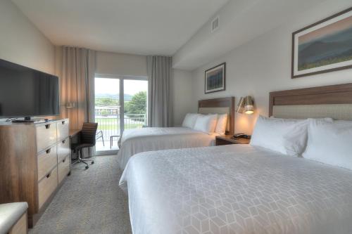 a hotel room with two beds and a flat screen tv at Holiday Inn & Suites Pigeon Forge Convention Center by IHG in Pigeon Forge