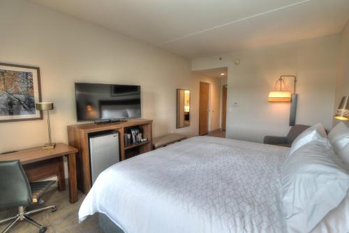 a hotel room with a bed and a flat screen tv at Holiday Inn & Suites Pigeon Forge Convention Center by IHG in Pigeon Forge