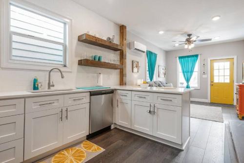 a kitchen with white cabinets and a yellow door at Franks Farmhouse Shotgun style apt in Ybor City in Tampa