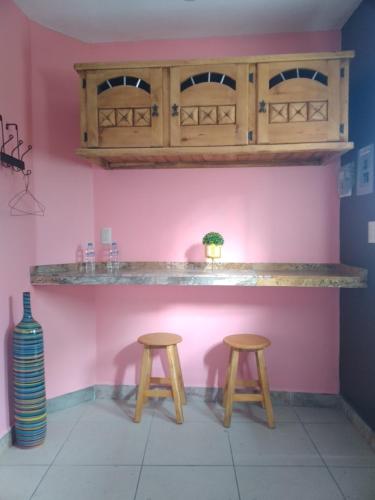 a bar with two stools and a pink wall at Hospedaje Casa Verde in Tepoztl&aacute;n