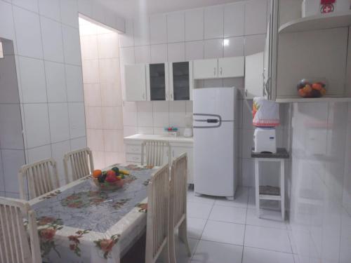 a kitchen with a table and a white refrigerator at Casa Familiar - Guaibim in Guaibim