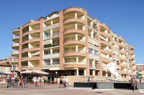 a large building with people walking in front of it at Residence Mediterraneo in Marina di Grosseto